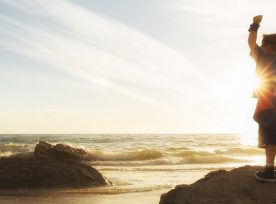 Young Boy Dressed As Superhero At Beach During Sunset