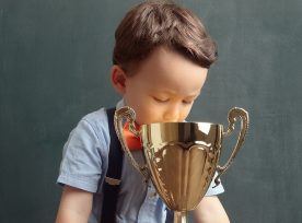 Little Boy Smiling With A Golden Trophy