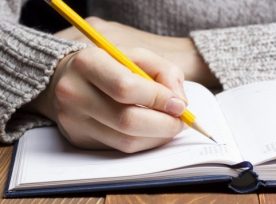 Female Hands With Pencil Writing On Notebook