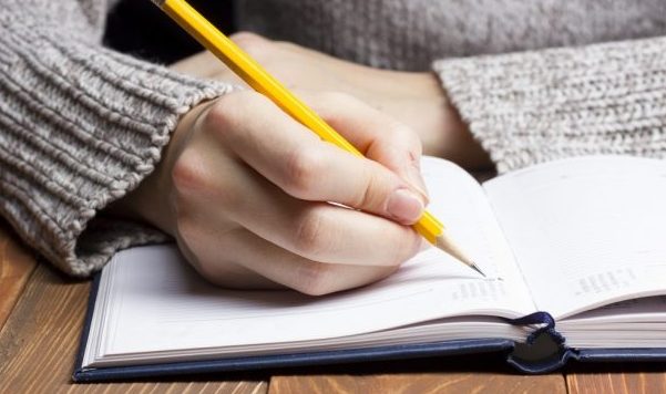Female Hands With Pencil Writing On Notebook