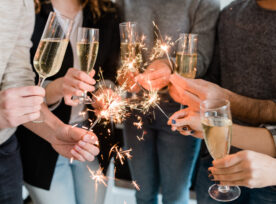 Group Of Friends Holding Flutes Of Sparkling Champagne And Burning Bengal Lights