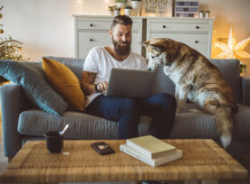 A man working on his laptop sitting with his dog