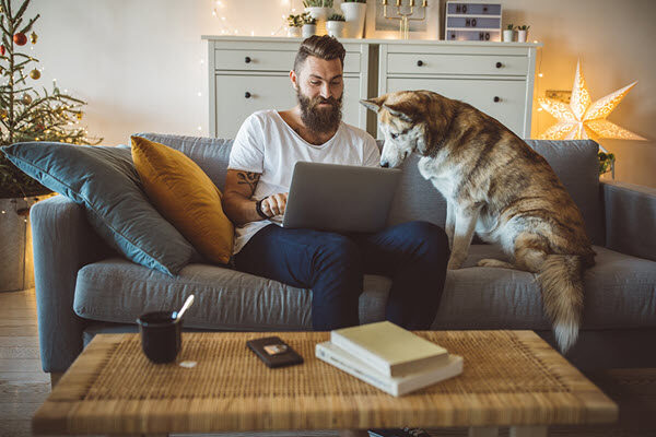 A man working on his laptop sitting with his dog