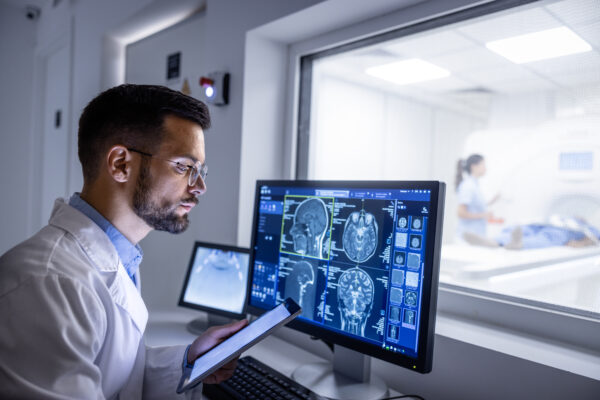 Doctor Examining X Ray Images In Mri Control Room.