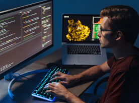 Closeup Of Program Developer Writing Software On Multiple Computer Screens At Home Office