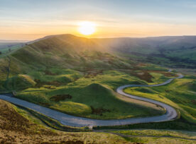 Sunset At Mam Tor In The Peak District With Long Winding Road Leading Through Valley.