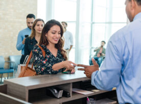 Woman Hands Debit Card To Unrecognizable Bank Teller