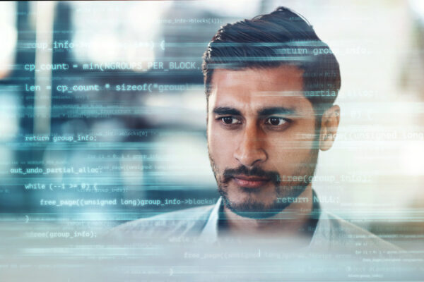 Digitally Enhanced Shot Of A Handsome Businessman Working In The Office Superimposed Over Multiple Lines Of Computer Code