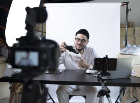 Asian Man Blogger Or Vlogger Looking At Camera Reviewing Product.