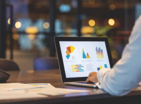 Close Up Of Businessman Using A Laptop With Graphs And Charts On A Laptop Computer.