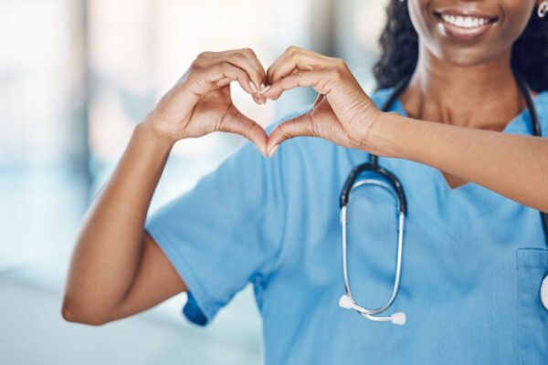 Closeup African American Woman Nurse Making A Heart Shape With Her Hands While Smiling And Standing In Hospital. Take Care Of Your Heart And Love Your Body. Health And Safety In The Field Of Medicine