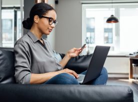 Young Woman Making Online Payment While Sitting In The Living Room On Sofa