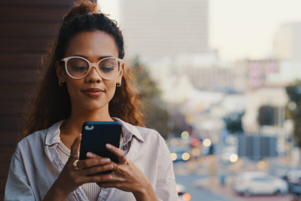 Shot Of An Attractive Young Businesswoman Texting While Standing Outside On The Office Balcony