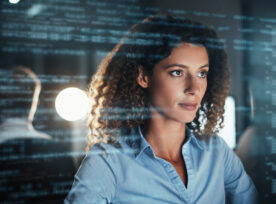 Digitally Enhanced Shot Of An Attractive Businesswoman Working In The Office Superimposed Over Multiple Lines Of Computer Code