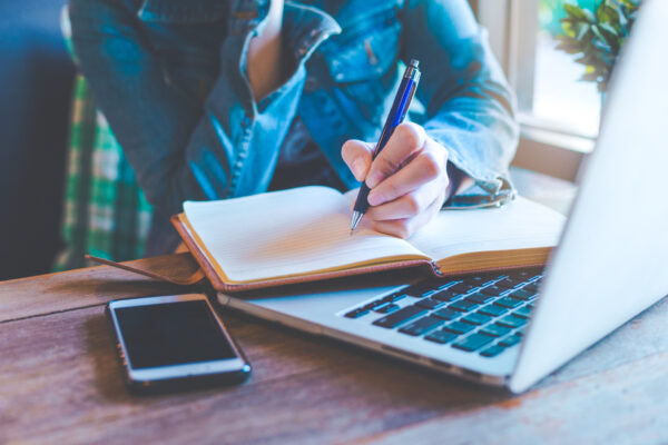 Woman Hands With Pen Writing On Notebook In The Office.