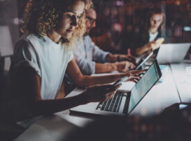 Team Of Young Coworkers Work Together At Night Office.young Woman Using Smartphone At The Table.horizontal.blurred Background.