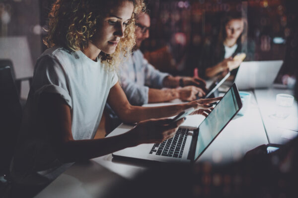 Team Of Young Coworkers Work Together At Night Office.young Woman Using Smartphone At The Table.horizontal.blurred Background.