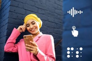 Young-Woman-Leaning-Against-A-Blue-Brick-Wall-And-Looking-At-Cell-Phone