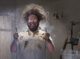 Funny picture of a man holding frayed electrical wires, his hair is standing on end with face scorched.