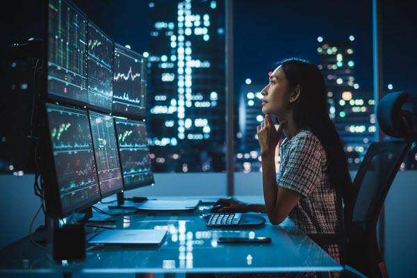 Portrait of a Financial Analyst Working on Computer with Multi-Monitor Workstation with Real-Time Stocks, Commodities and Exchange Market Charts.