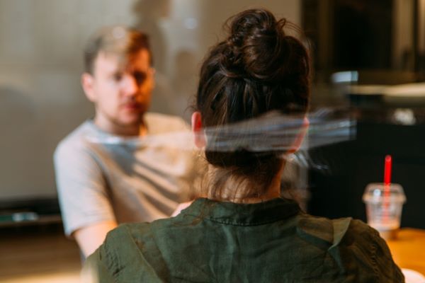 The pain of honest evaluations shown by a photo of looking through glass at two people talking.