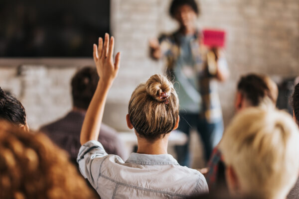 Back View Of A Woman Wants To Ask A Question On A Seminar.