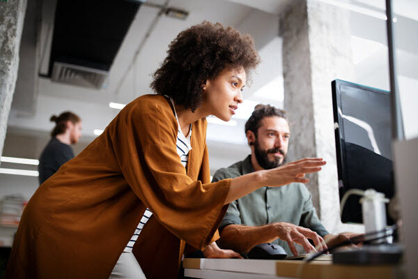 A man and woman collaborating and discussing work on a computer