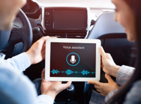 Couple Using Voice Assistant On Tablet Sitting In Car, Back View