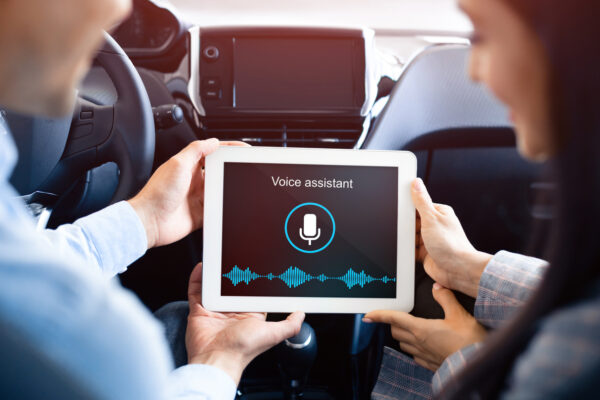 Couple Using Voice Assistant On Tablet Sitting In Car, Back View