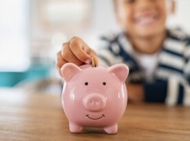 Little kid putting a coin in a piggy bank