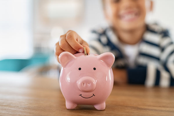 Little kid putting a coin in a piggy bank