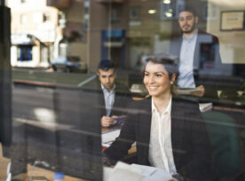 Group Of Happy Workers Behind A Window Looking At Computer From Their Office