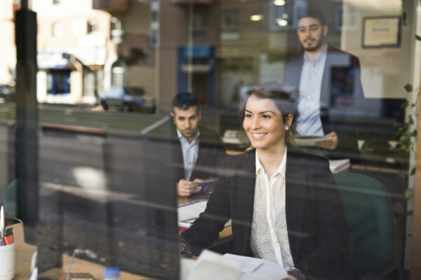 Group Of Happy Workers Behind A Window Looking At Computer From Their Office