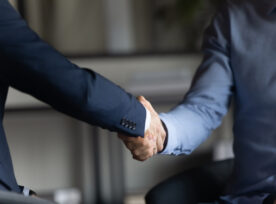 Two Businessmen In Formal Suits Shaking Hands After Successful Negotiations