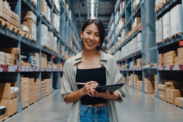 Portrait of Asian woman holding a digital tablet stand in a supply warehouse