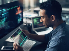 Shot Of A Young Man Using His Digital Tablet And Computer In A Modern Office