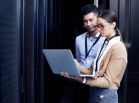 Shot Of Two Technicians Working Together In A Server Room