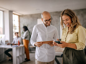 Businessman and businesswoman smiling looking at phone stock photo