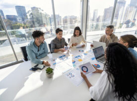 group of people working with Paperwork on a board room table at a business presentation or seminar.