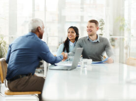 Happy Diverse Couple Shaking Hands With Insurance Agent In The Office.