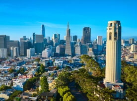 Aerial Coit Tower In Late Afternoon With Downtown San Francisco Skyscrapers And Distant Bridge