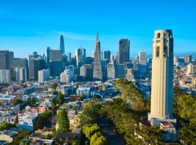 Aerial Coit Tower In Late Afternoon With Downtown San Francisco Skyscrapers And Distant Bridge