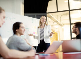 Businesswoman Giving Presentation On Future Plans To Colleagues