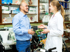 Female Consultant Offering Wheelchair To Mature Customer