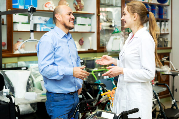 Female Consultant Offering Wheelchair To Mature Customer