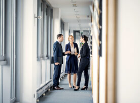 Business Professionals Discussing In Office Corridor