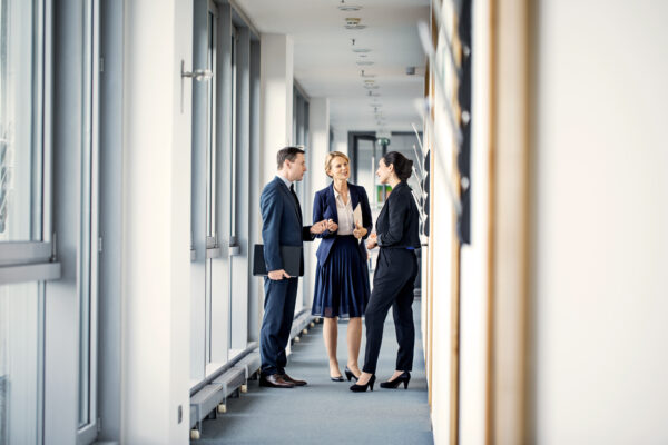 Business Professionals Discussing In Office Corridor