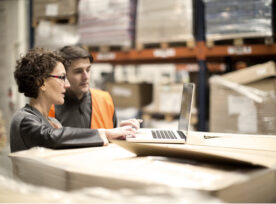 Two people working on a laptop in a warehouse