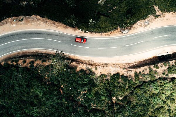 A red car driving down and winding road
