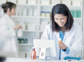 Female Pharmacist Uses Computer In Pharmacy